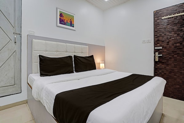 Un dormitorio con cama, mesita de noche, lámpara de pared y una puerta.