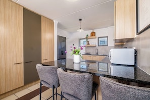 A modern kitchen with a central island, bar stools, a refrigerator, and a white oven. - Haus 189 Dainfern- Pool Play Area Power Backup (Johannesburg)