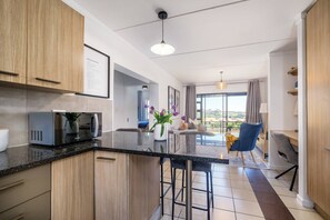 A modern kitchen with a central island, bar stools, and a view to the outside. - Haus 189 Dainfern- Pool Play Area Power Backup (Johannesburg)