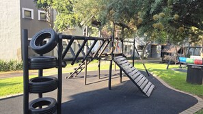 Ein Spielplatz mit Rutsche, Reifenwand und Schaukeln.