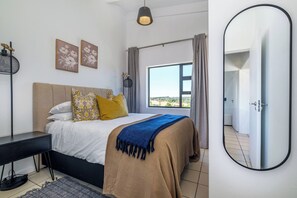 A bedroom with a bed, bedside table, lamp, and a large window with curtains. - Haus 189 Dainfern- Pool Play Area Power Backup (Johannesburg)