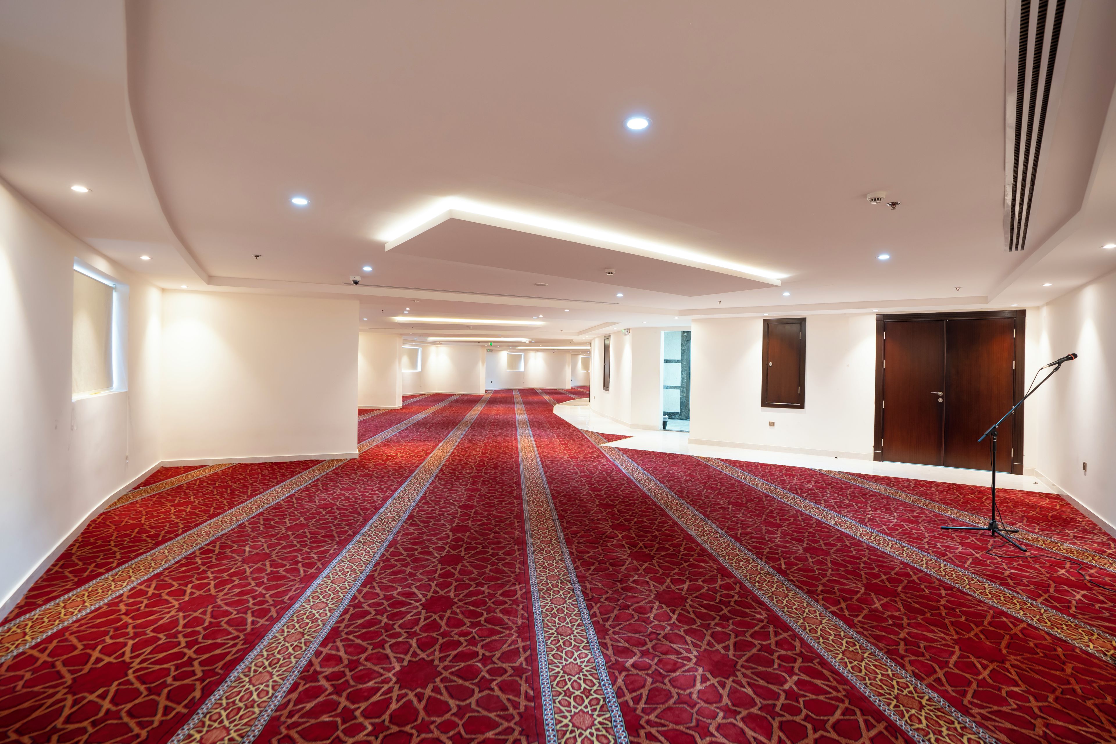 Un vaste hall d’entrée avec un tapis rouge, des murs blancs et un pied de micro.