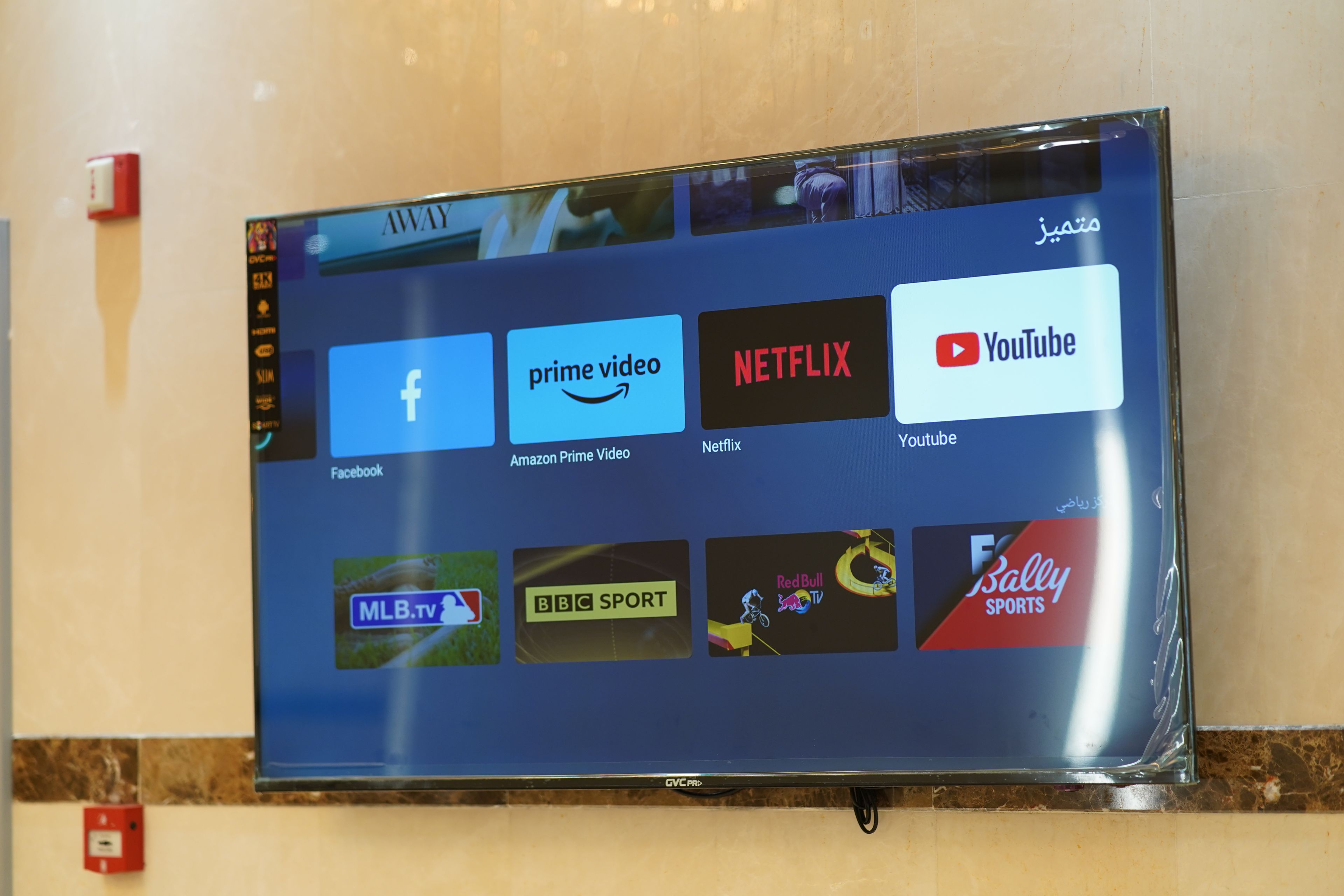 A flat-screen TV mounted on a wall displaying various streaming service icons.