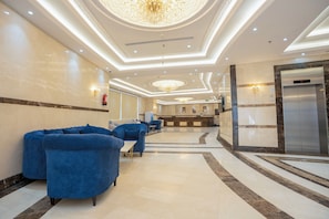 A hotel lobby with a reception desk, seating area, and an elevator. - Manazil Al Maqam Hotel (Makkah)