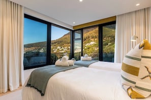Ein Hotelzimmer mit zwei Betten, großen Fenstern und Blick auf eine Berglandschaft.