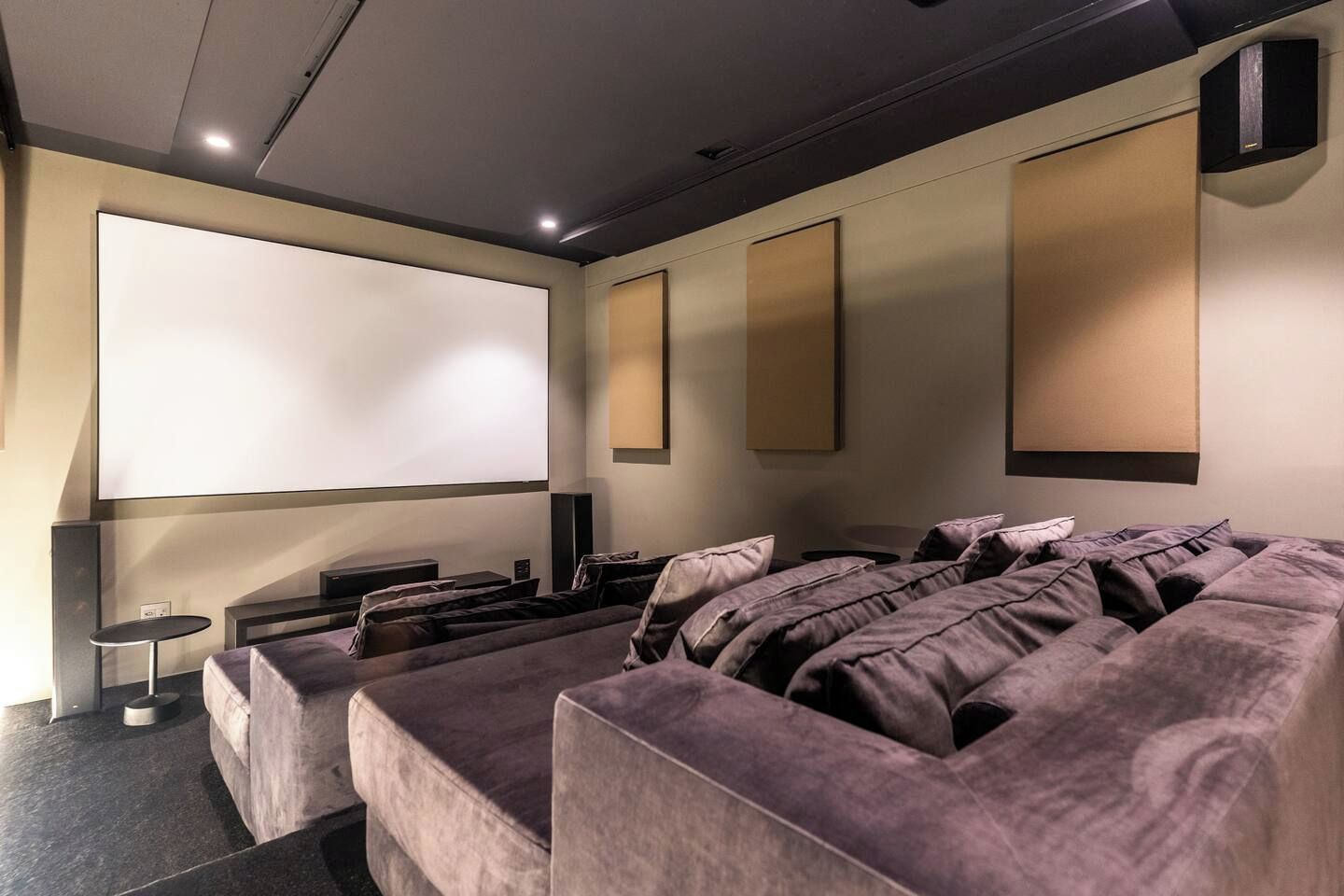 A home theater room with a large screen, comfortable seating, and a speaker system.
