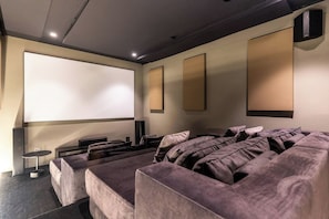 A home theater room with a large screen, comfortable seating, and a speaker system. - Hill House heated infinity pool & kids' paradise (Cape Town)