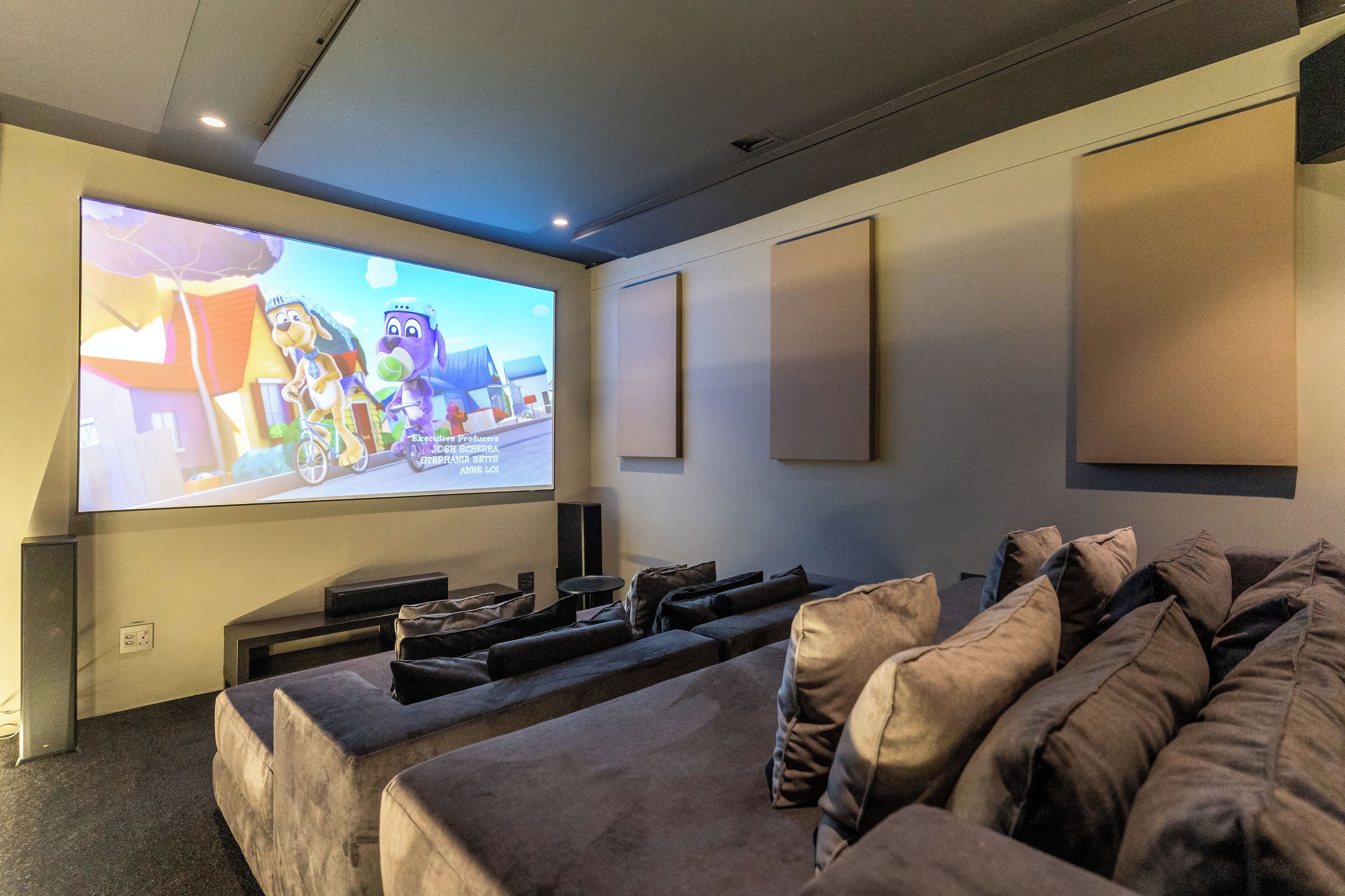 A home theater room with a large flat-screen TV, a sofa, and a speaker system.