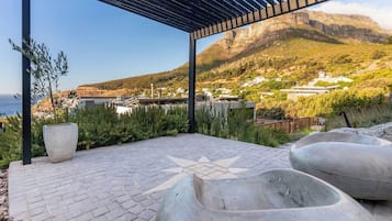 An outdoor patio with a star-shaped design, a pergola, and a view of a mountainous landscape with buildings in the distance.