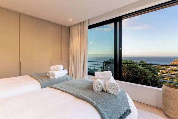 A hotel room with a large bed, a view of the sea, and a balcony. - Hill House heated infinity pool & kids' paradise (Cape Town)