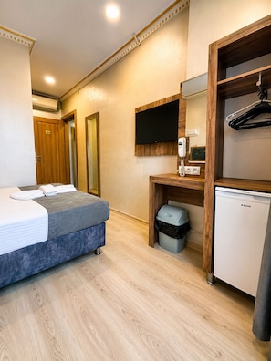 A hotel room with a bed, a desk with a telephone, a television, and a mini-fridge. - Neva Hotel (İstanbul)