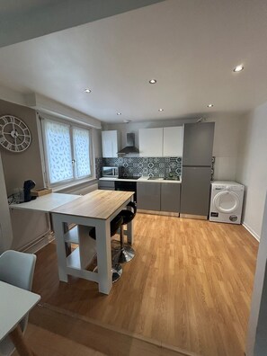 A compact kitchen with a dining area, a microwave, a refrigerator, and a washing machine. - Vrbo Property (Lingolsheim)
