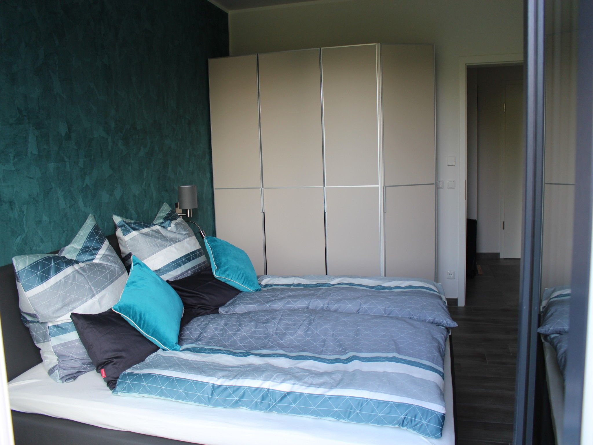 Ein Schlafzimmer mit einem Bett, Kissen, einer Nachttischlampe und einem Kleiderschrank.