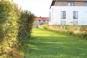 A well-maintained grassy area with a hedge and a modern building in the background. - Apartment 'Casa Tunix' with Private Pool, Private Terrace and Wi-Fi (Göhren-Lebbin)