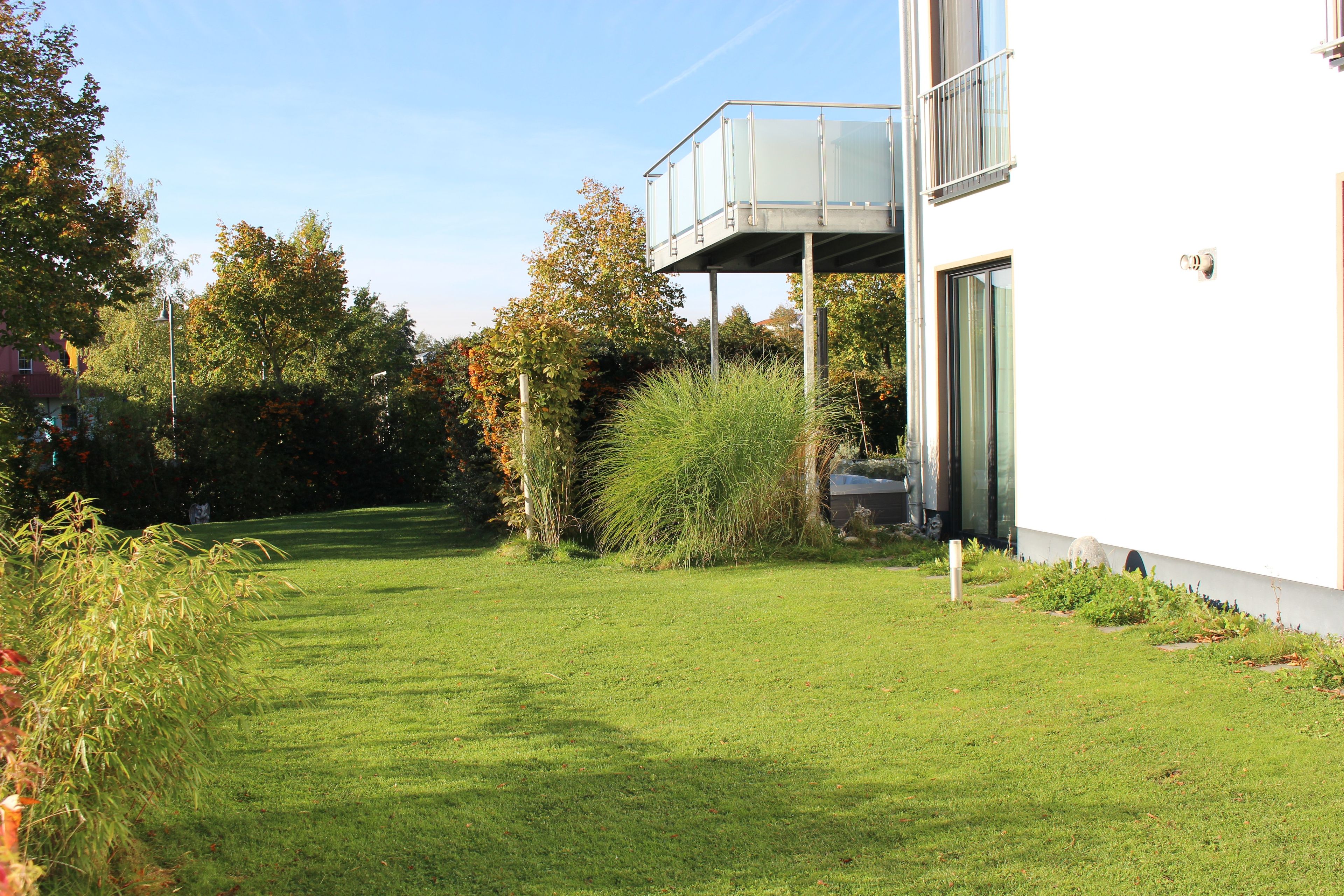Un bâtiment moderne doté d’un toit plat, d’un balcon en verre et d’une pelouse bien entretenue.