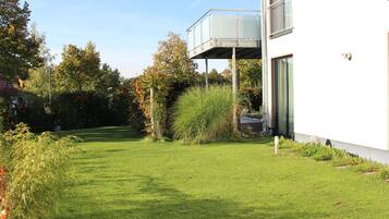 Un bâtiment moderne doté d’un toit plat, d’un balcon en verre et d’une pelouse bien entretenue.