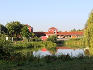 A tranquil lakeside setting with a red building, a small red structure, and lush greenery. - Apartment 'Casa Tunix' with Private Pool, Private Terrace and Wi-Fi (Göhren-Lebbin)