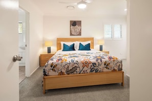 A bedroom with a wooden bed, two bedside lamps, a ceiling fan, and a window with blinds. - Marea by Khove - Kingscliff (Kingscliff)
