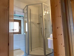 A glass-enclosed shower stall with a white tiled floor, a visible toilet, and a towel rack above the toilet. - 34-square-meter apartment with a balcony and a lake view (Gstadt am Chiemsee)