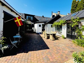 A courtyard with a paved walkway, outdoor seating, and a flag.