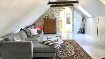 A loft-style room with a grey sectional sofa, a small round table, and a patterned rug.