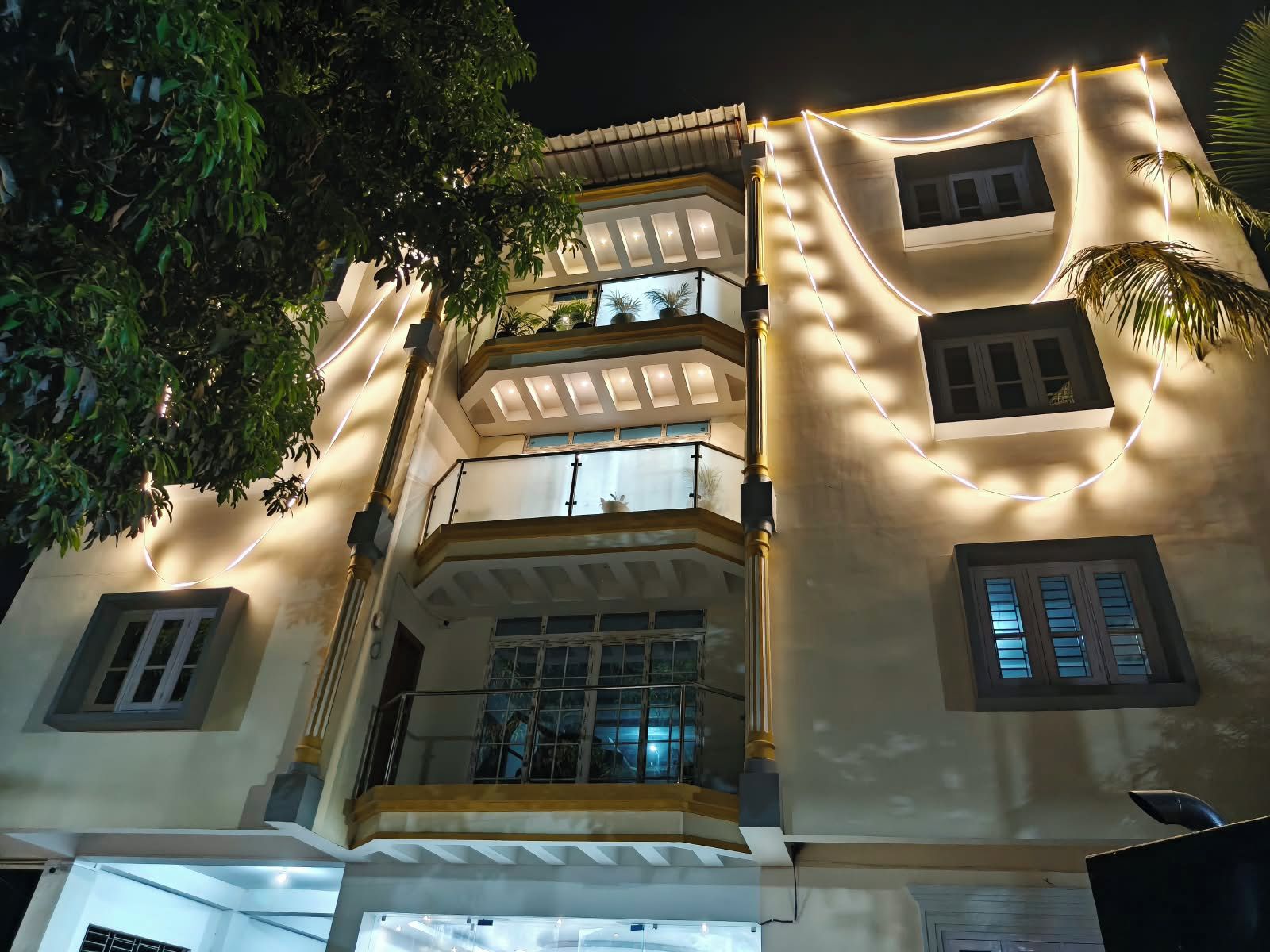 A multi-story building with balconies and windows, illuminated by string lights.