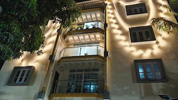 A multi-story building with balconies and windows, illuminated by string lights.