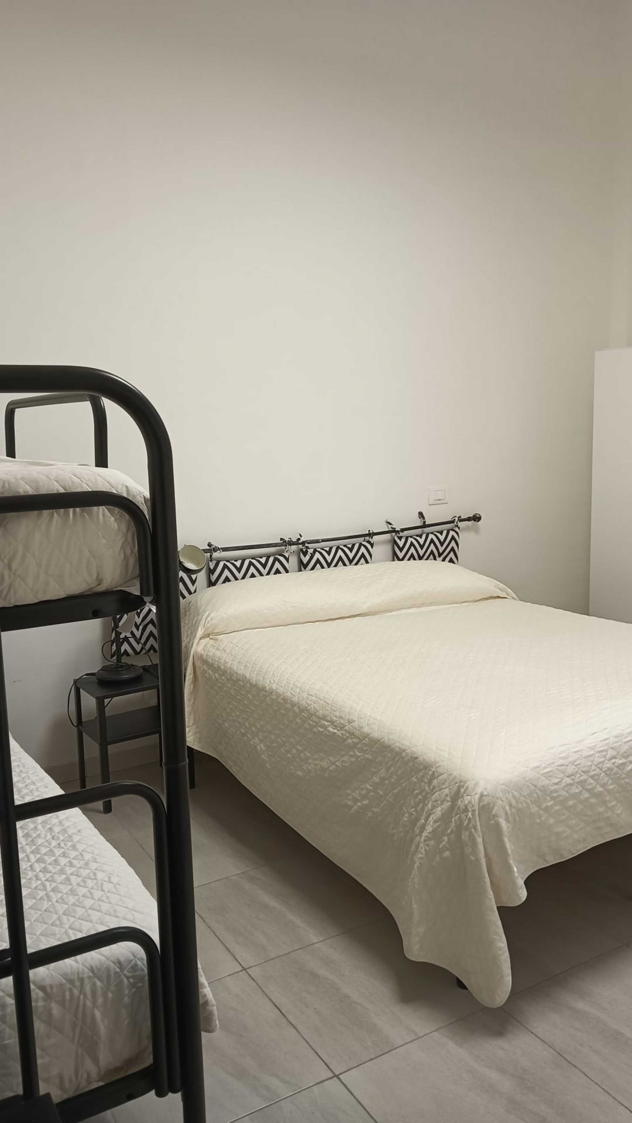 Un letto a castello con un letto inferiore, un comodino e un letto con testiera decorata.