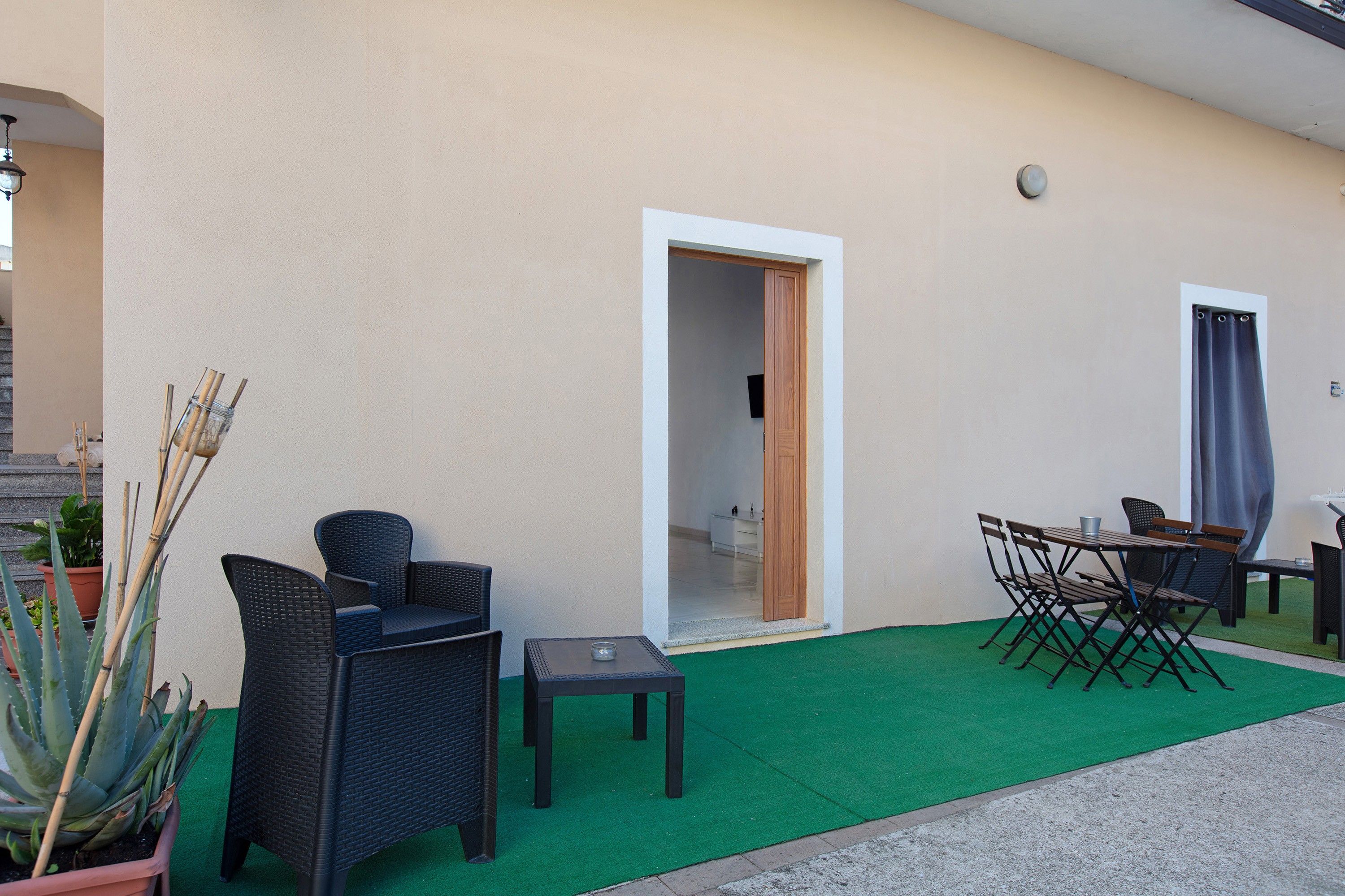 An outdoor seating area with wicker furniture, a small table, and a potted plant.