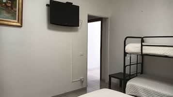 Une chambre avec des lits superposés, un téléviseur fixé au mur et une porte donnant sur un espace extérieur.