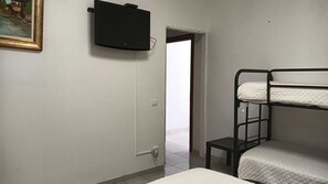 Une chambre avec des lits superposés, un téléviseur fixé au mur et une porte donnant sur un espace extérieur.