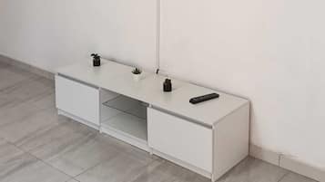 A white entertainment unit with a flat-screen TV mounted on the wall above it.