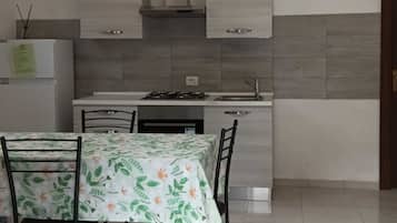 Une cuisine moderne avec des meubles blancs, une cuisinière à gaz et un coin repas comprenant une table et des chaises.