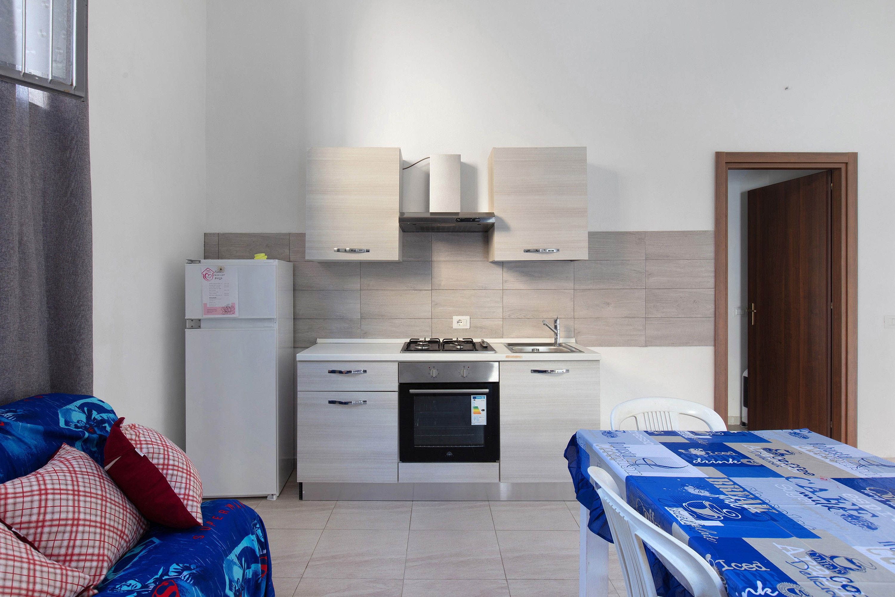 A compact kitchenette with a refrigerator, stove, oven, and a small sink.