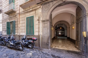 A building entrance with a stone facade, green shutters, and a series of parked motorcycles. - Satriano Style Flat - Double Apartment (Naples)