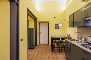 A compact kitchen with a dining area, a refrigerator, a stove, and a small table with chairs. - Satriano Style Flat - Double Apartment (Naples)