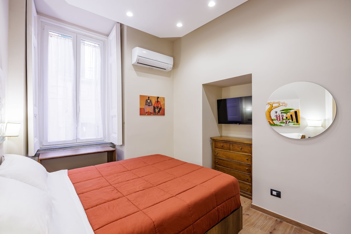 A bedroom with a bed, a dresser, a mirror, and a television.