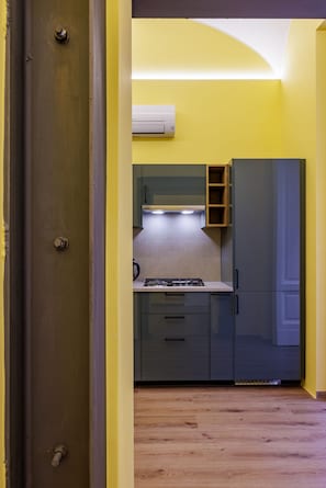 A compact kitchen with a gas stove, cabinets, and an air conditioning unit. - Satriano Style Flat - Double Apartment (Naples)
