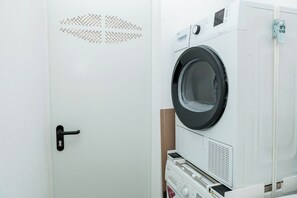 A white door with a black handle and a circular window on a white appliance, likely a washer and dryer, with a control panel and a warning label. - Top Floor 2 Bedroom Apartment with Terrace. Next to City of Arts & Oceanografic (València)