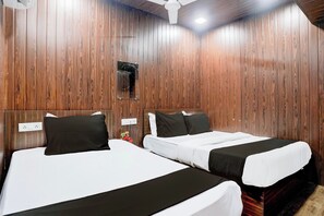 Een kamer met twee bedden, houten lambrisering, een plafondventilator en een kleine spiegel.