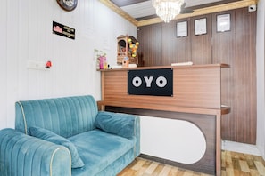 Una mesa de recepción con un letrero que dice 'OYO' y un sofá azul al frente.