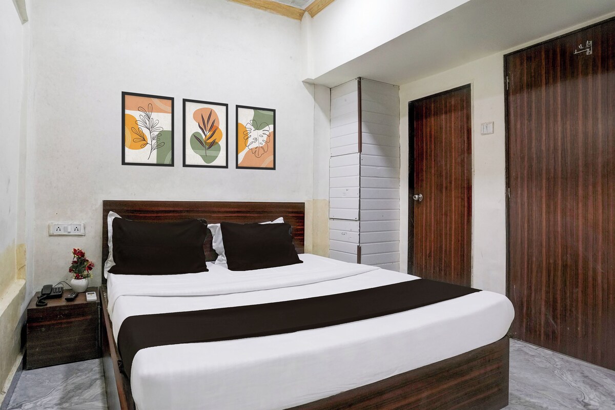Een slaapkamer met een bed, nachtkastje en een wandcontactdoos.