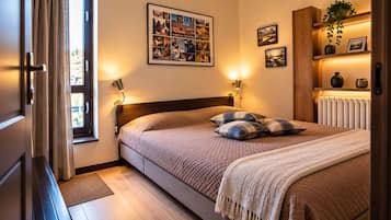 Un dormitorio con cama, lámparas de noche, un collage enmarcado en la pared y un radiador.