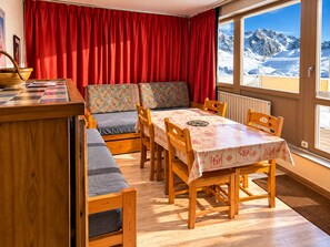 Une pièce chaleureuse avec une table en bois, des bancs et une vue sur des montagnes enneigées.