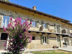 Un bâtiment à deux étages, avec des murs en pierre et une façade jaune, agrémenté de balcons et de fenêtres à volets.