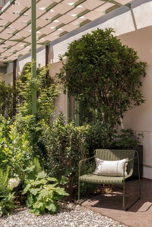 A covered outdoor seating area with a bench and a variety of plants. - Serra Novecento Garden Suite & Residence _La Veranda_ (Bellano)