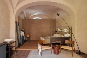 A compact bedroom with a bed, bedside table, chair, and a desk with a lamp. - Serra Novecento Garden Suite & Residence _La Veranda_ (Bellano)