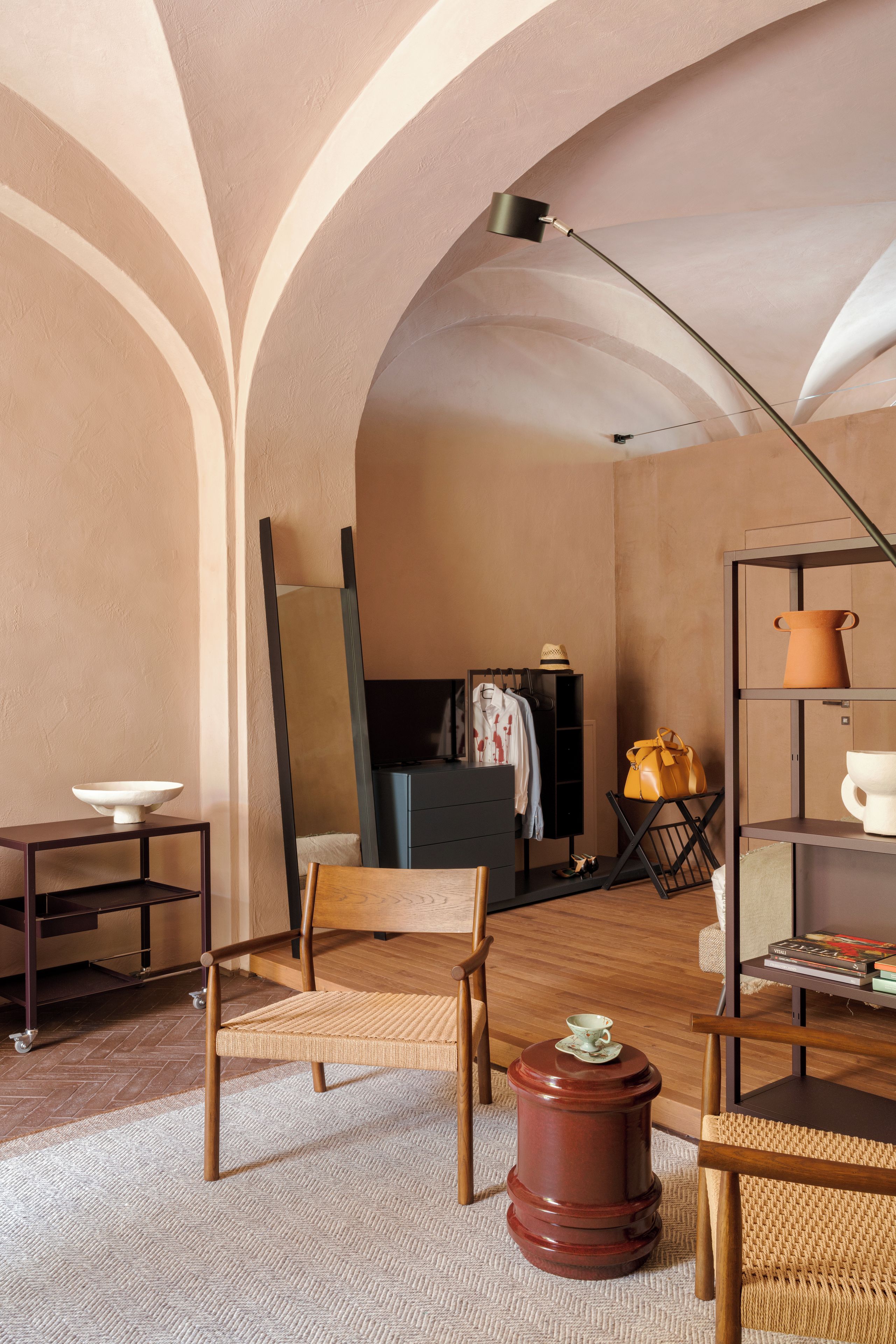 A room with a wooden chair, a small table, a floor lamp, and a shelf with decorative items.