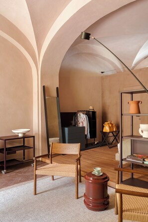 A room with a wooden chair, a small table, a floor lamp, and a shelf with decorative items. - Serra Novecento Garden Suite & Residence _La Veranda_ (Bellano)