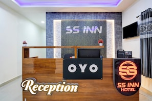 Ein Empfangsbereich mit einem Schild, auf dem 'SS INN HOTEL' steht, und einer digitalen Anzeige, die 'Rezeption' anzeigt.